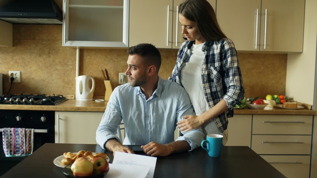 A couple reviewing paperwork together at a kitchen table