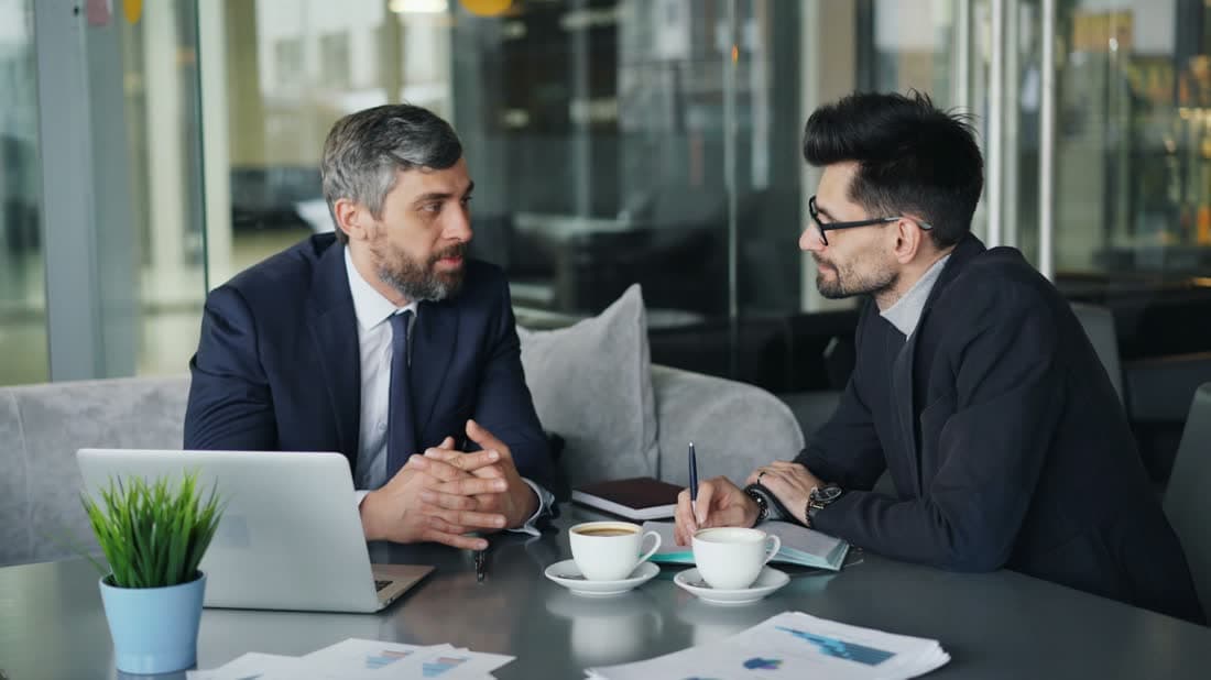 Two men in conversation at a table